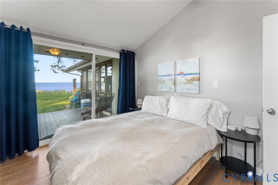 Sliding glass door, vaulted ceiling, and wood-finish flooring