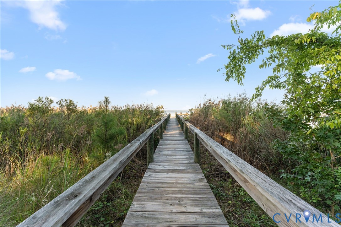 Elevated wooden boardwalk featuring side railings and natural vegetation surroundings