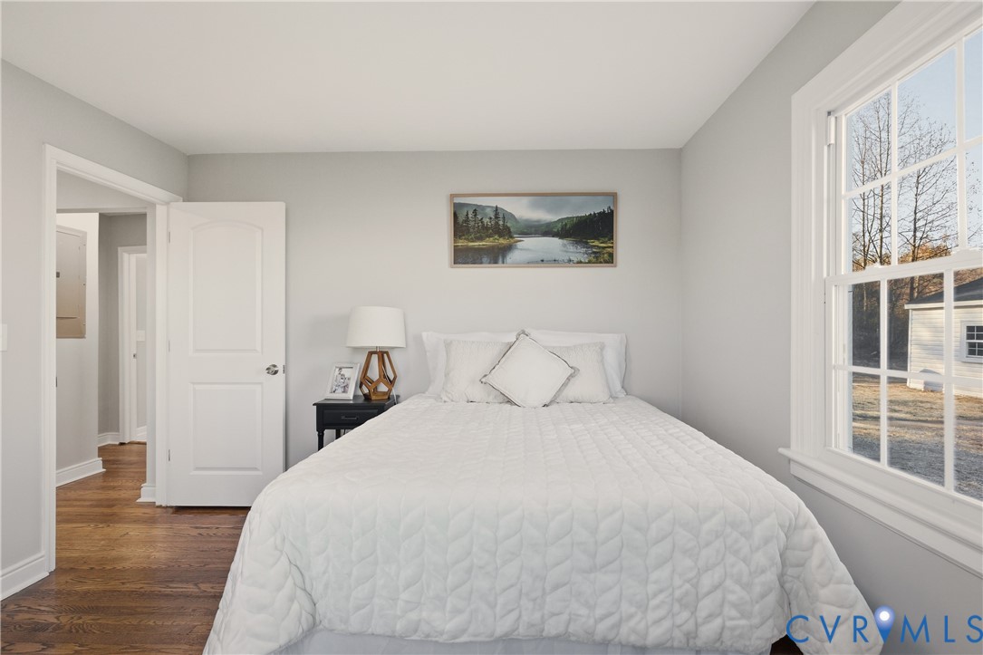 Room featuring neutral wall paint, wood-finish flooring, and a multi-pane window with exterior trim