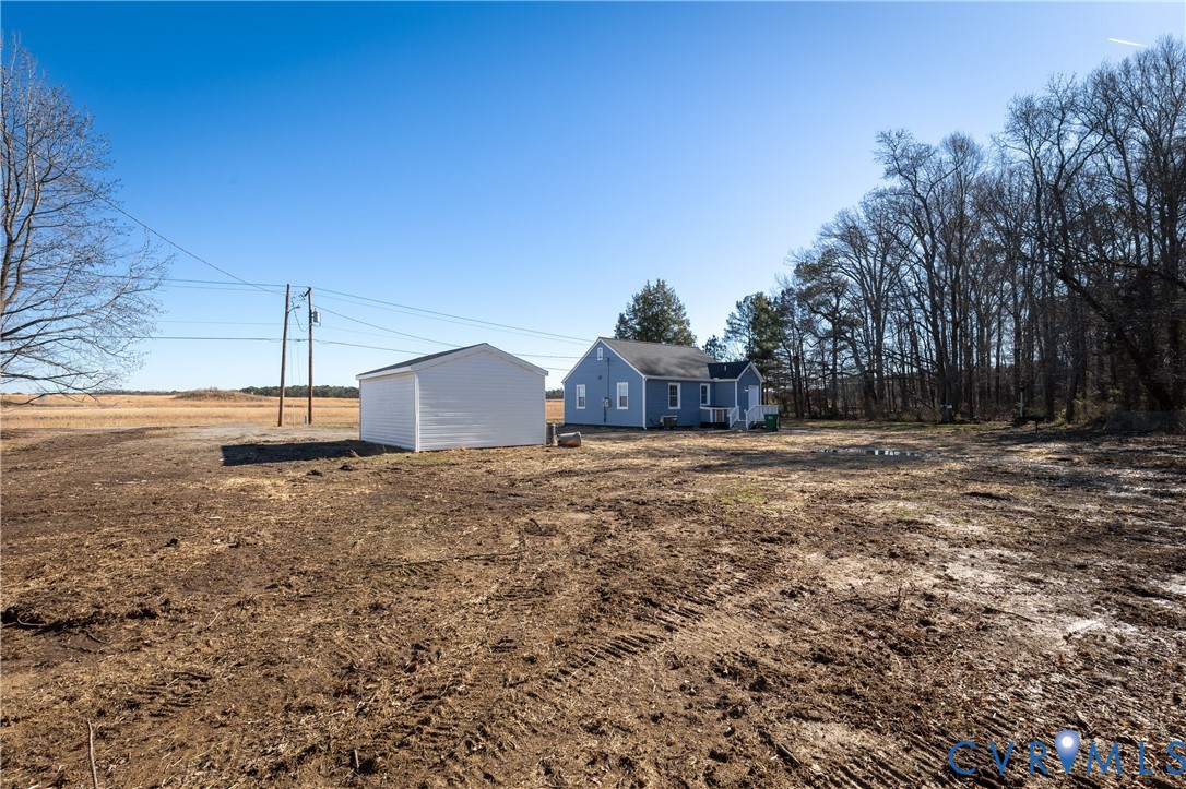 Detached dwelling with a neutral-toned exterior, standalone storage structure, and expansive acreage