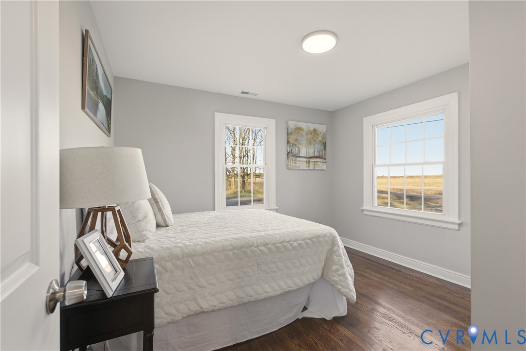 Interior room featuring wood-finish flooring, two large windows with grid muntins, and neutral wall paint