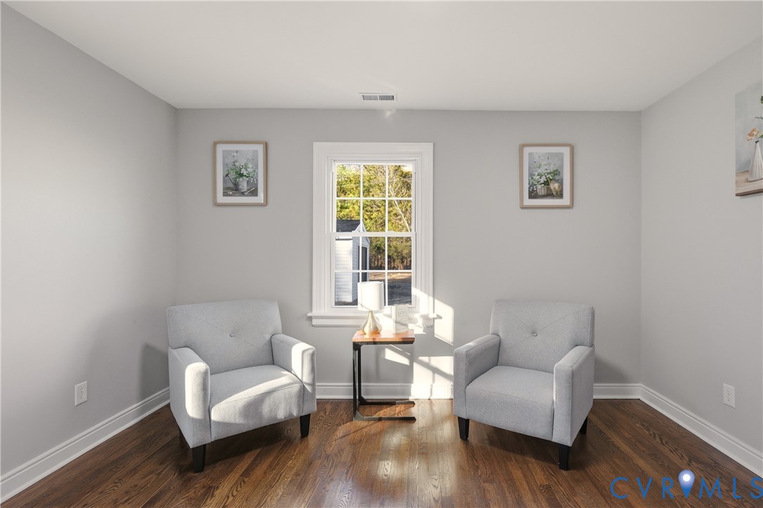 Neutral-toned interior space featuring wood-finish flooring and a multi-pane window with white trim