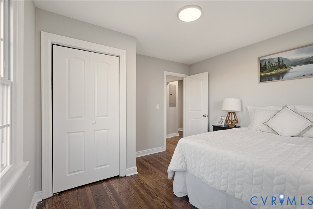 Interior room featuring wood-finish flooring, white paneled doors, neutral wall paint, and a ceiling-mounted flush lighting fixture