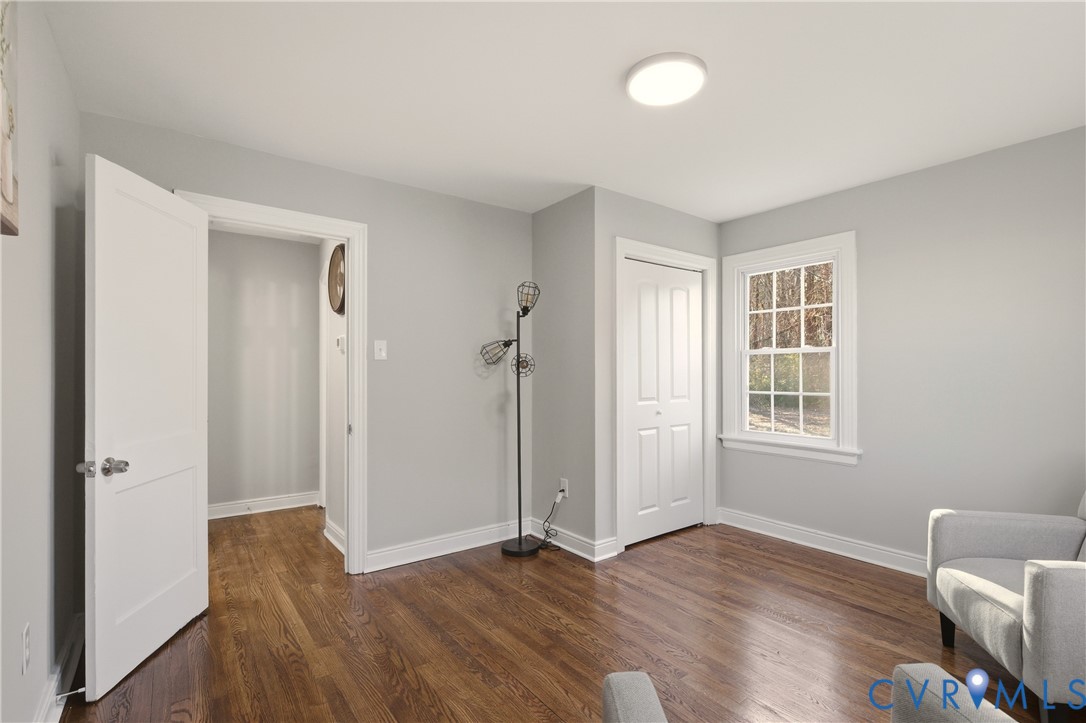 Wood-finish flooring, multi-pane window with white trim, and two-panel interior doors