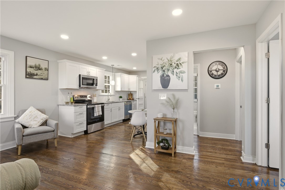 Kitchen featuring white cabinetry, stainless steel appliances, and wood-finish flooring complemented by recessed lighting