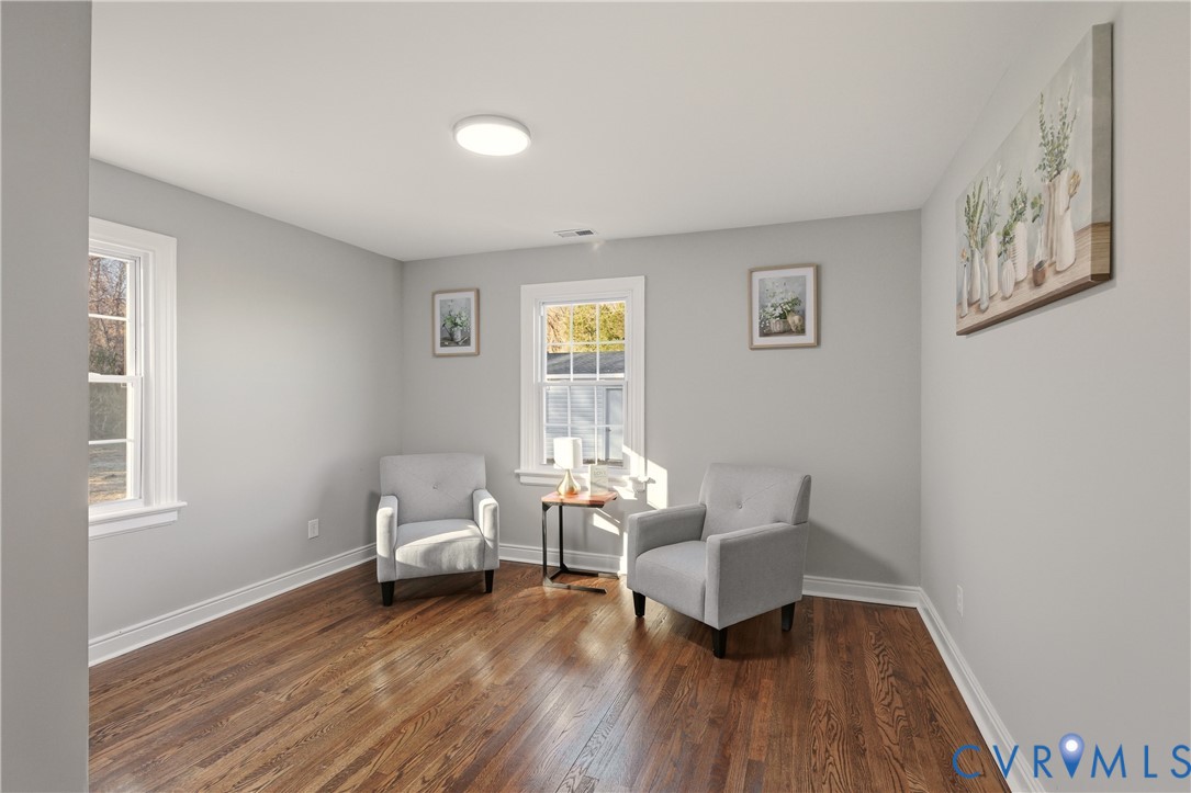 Interior room featuring wood-finish flooring, neutral wall paint, and multi-pane windows with white trim