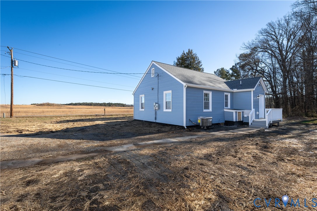 Blue horizontal lap siding exterior featuring a gable roof, white-trimmed windows, and a raised wooden deck with white railing