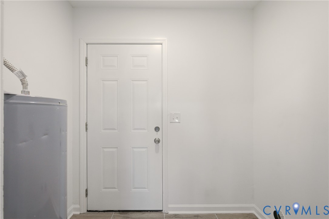 Utility area featuring a six-panel door, neutral wall paint, and stone-finish tile flooring
