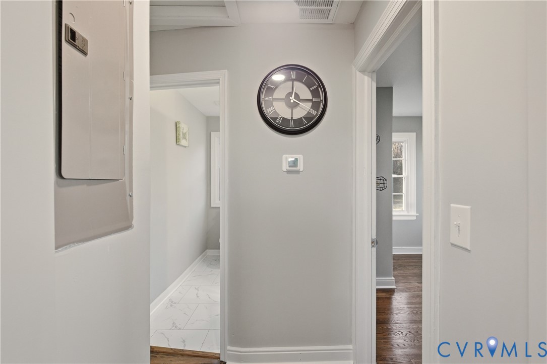 Hallway featuring neutral wall paint, wood-finish flooring, and white door trim