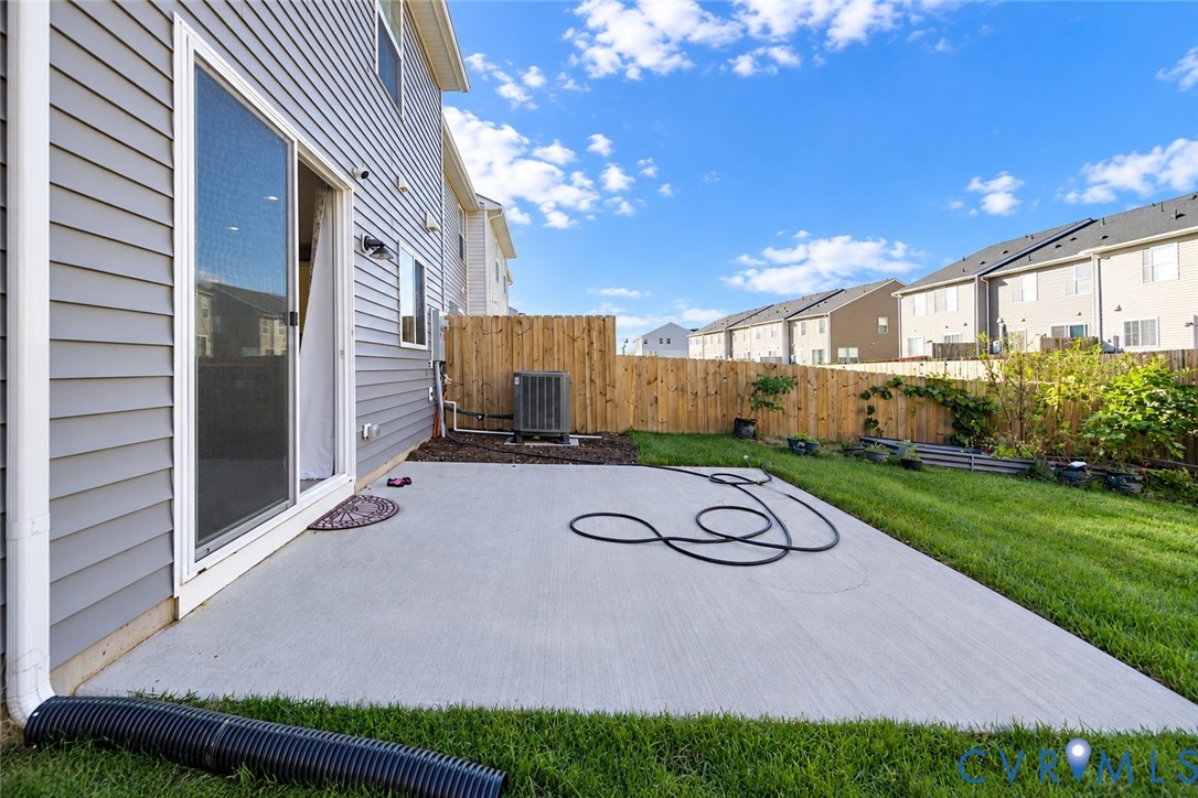 Concrete patio with horizontal vinyl siding, sliding glass door, and wooden privacy fencing
