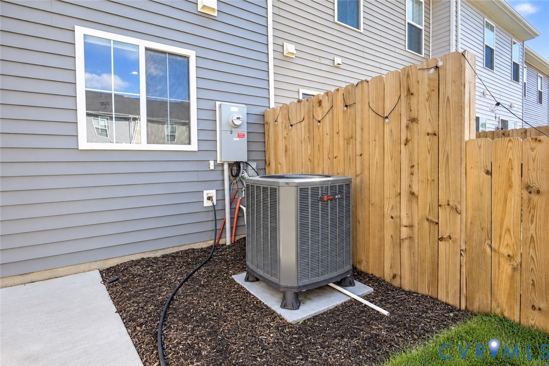 Exterior space featuring light blue horizontal lap siding, wood privacy fencing, a concrete pad, and a ground-mounted HVAC unit