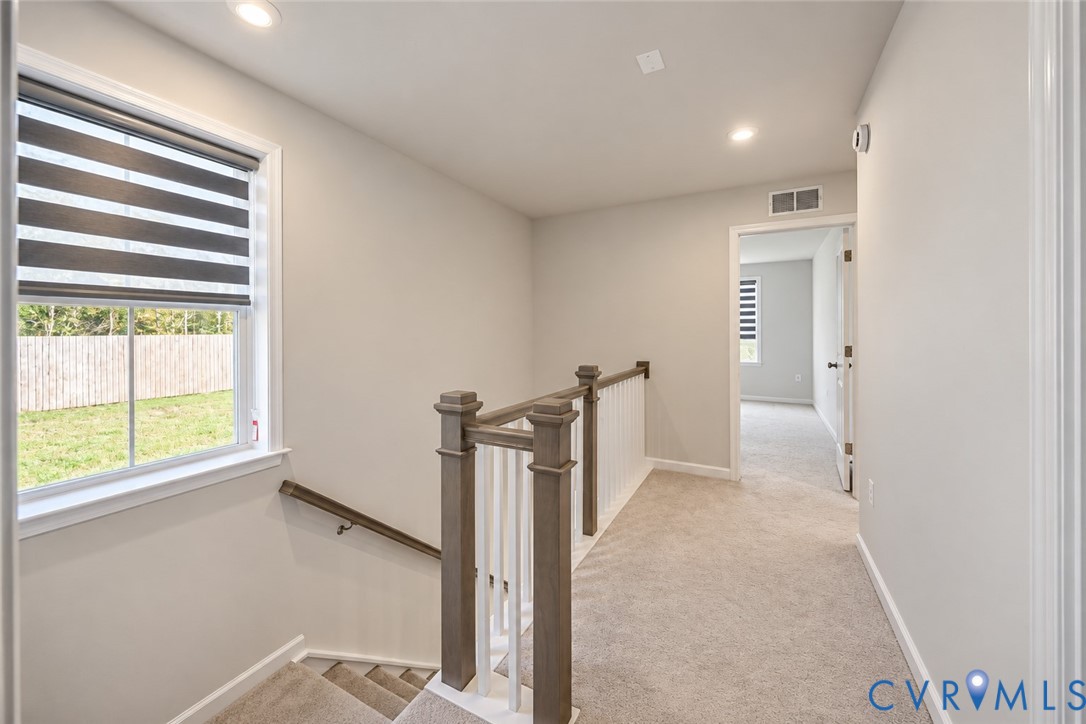 Staircase featuring wood-finish railings, white balusters, recessed lighting, and neutral-tone carpeting