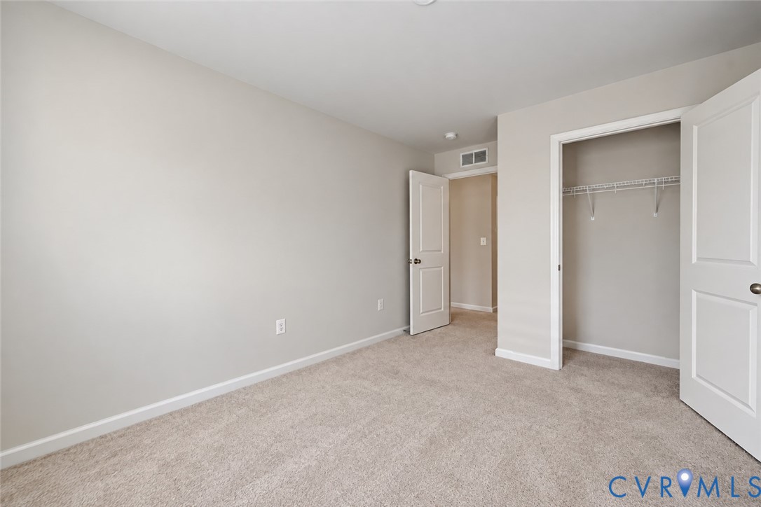 Neutral interior featuring wall-to-wall carpeting, two-panel interior doors, and a reach-in closet with integrated shelving