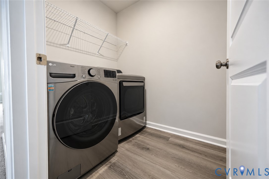 Laundry area featuring wood-finish flooring, neutral wall tones, and overhead wire shelving