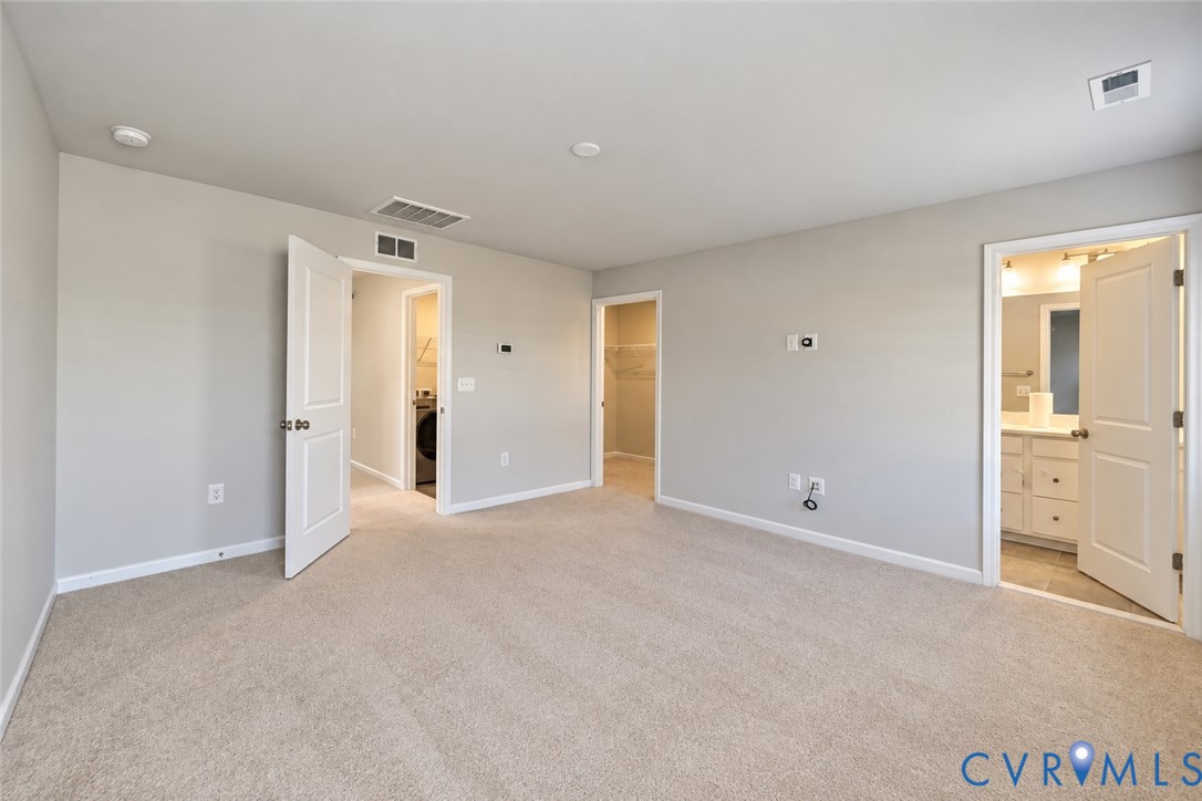 Neutral-toned interior featuring wall-to-wall carpeting, three-panel interior doors, and multiple walk-in storage areas
