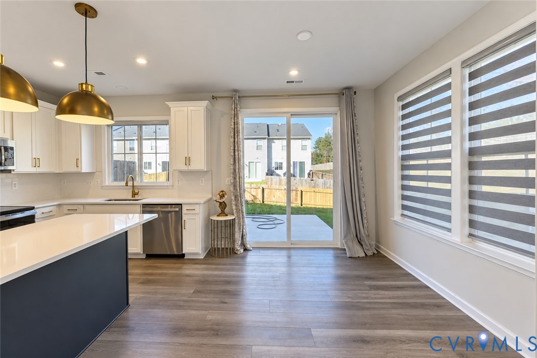 Kitchen featuring white cabinetry, quartz countertops, a contrasting dark-toned kitchen island, wood-finish flooring, and recessed lighting