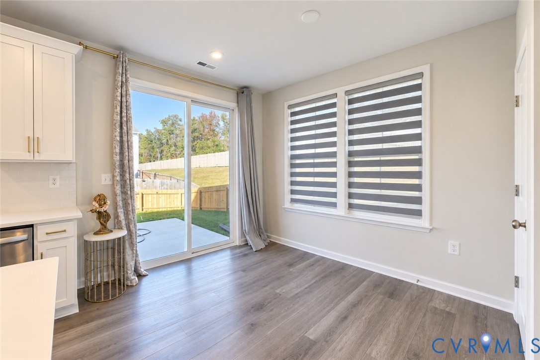 Wood-finish flooring, white shaker-style cabinetry with brass-tone hardware, and a sliding glass door opening to a concrete patio