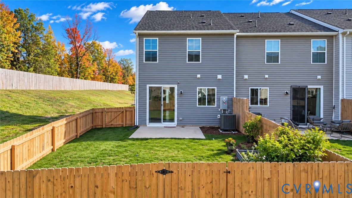 Grey horizontal siding exterior featuring a private backyard, wood-plank fencing, concrete patio, and sliding glass entry door