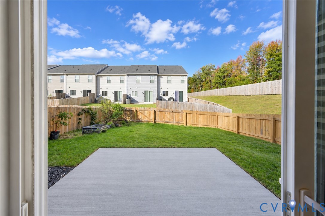 Concrete patio, fenced backyard, and grass lawn