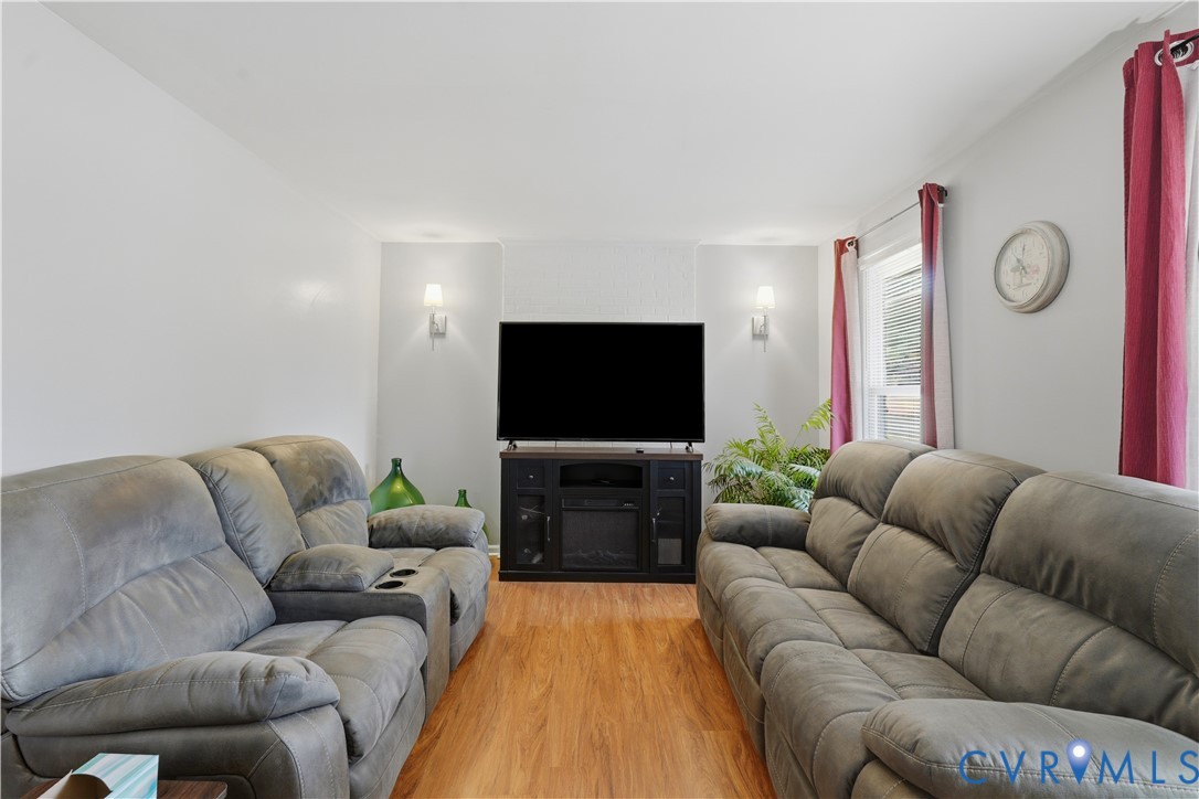 Living area featuring wood-finish flooring, two wall-mounted sconces, and a textured accent wall