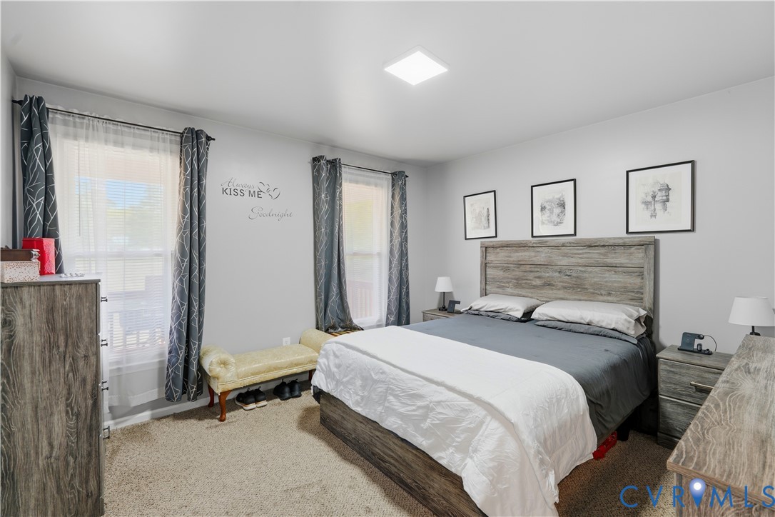 Neutral-toned room featuring wall-to-wall carpeting, flush-mount lighting, and dual windows