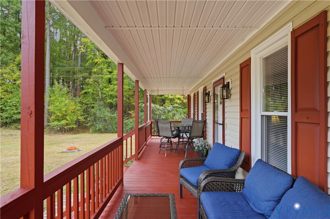 Covered front porch featuring painted wood decking, matching railings, vinyl siding, and window shutters