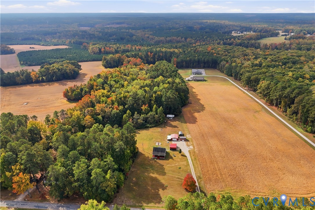 Expansive acreage featuring cleared agricultural fields, mature woodland, multiple outbuildings, and a gravel driveway