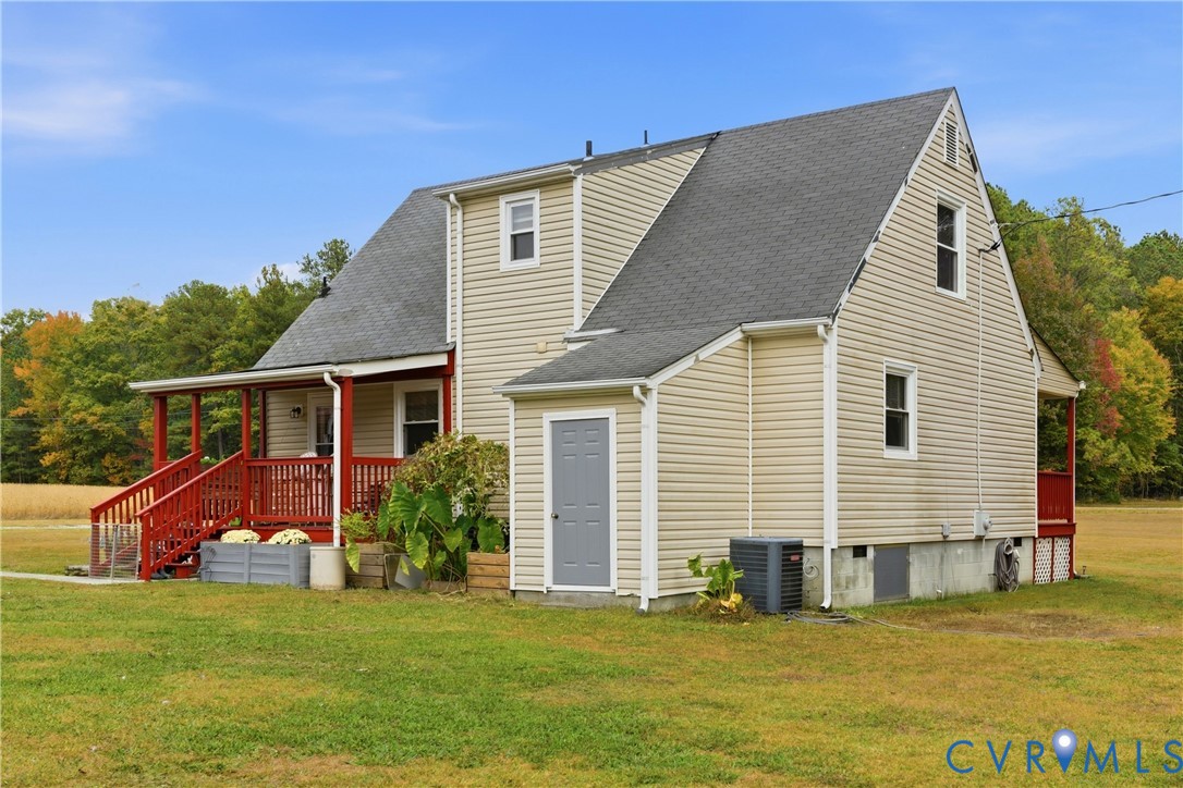 Two-story residence featuring light-colored horizontal siding, a gabled roofline, an expansive covered porch with red railings, and an integrated exterior storage unit