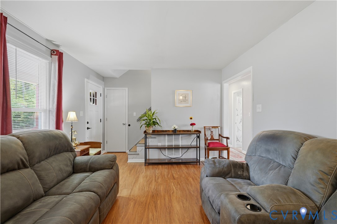 Interior space featuring wood-finish flooring, white door with glass panel inlay, and neutral wall color