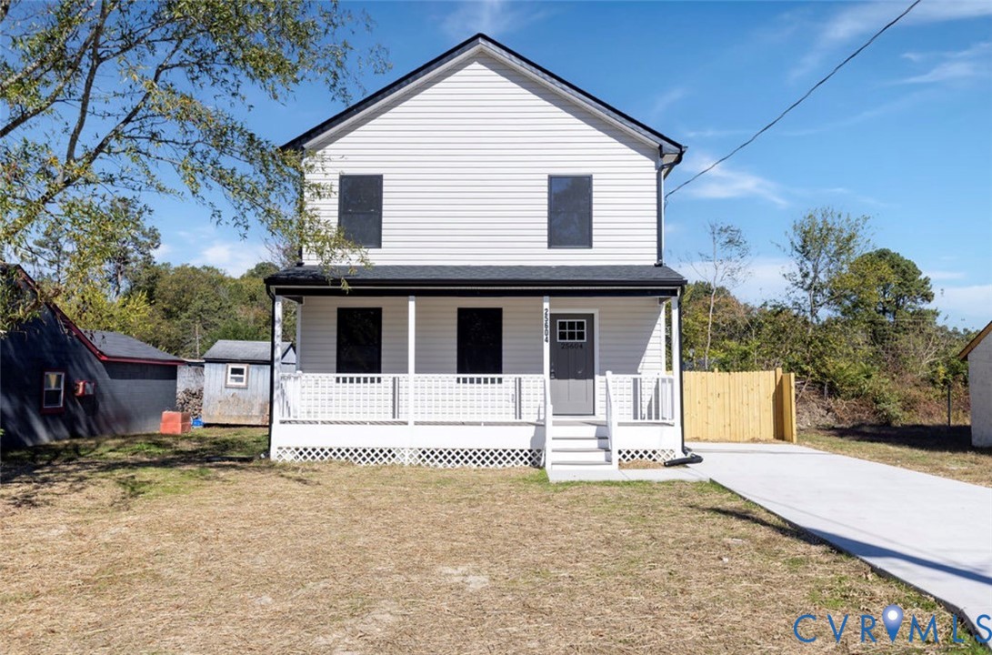 Two-story residence featuring white horizontal siding, a covered front porch with lattice skirting, a concrete driveway, and a fenced side yard