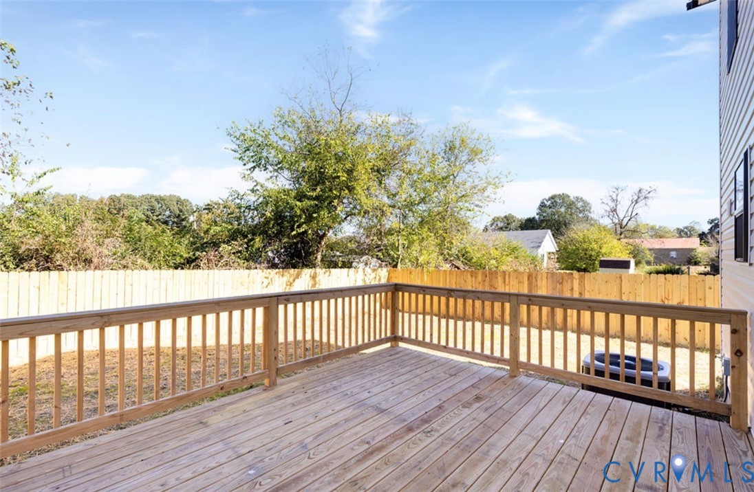 Elevated wood deck featuring vertical wood balusters and a wood privacy fence enclosing the backyard