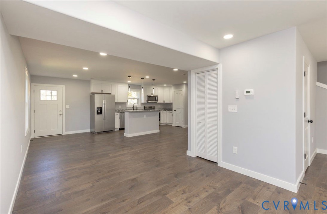 Kitchen featuring white shaker-style cabinetry, stainless steel appliances, stone-surface countertops, wood-finish flooring, and recessed ceiling lighting