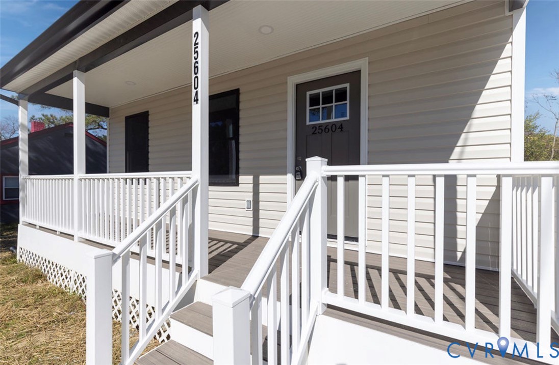 Covered front porch featuring light-colored horizontal siding, white railing, recessed lighting, and a single-entry door with a glass-pane insert