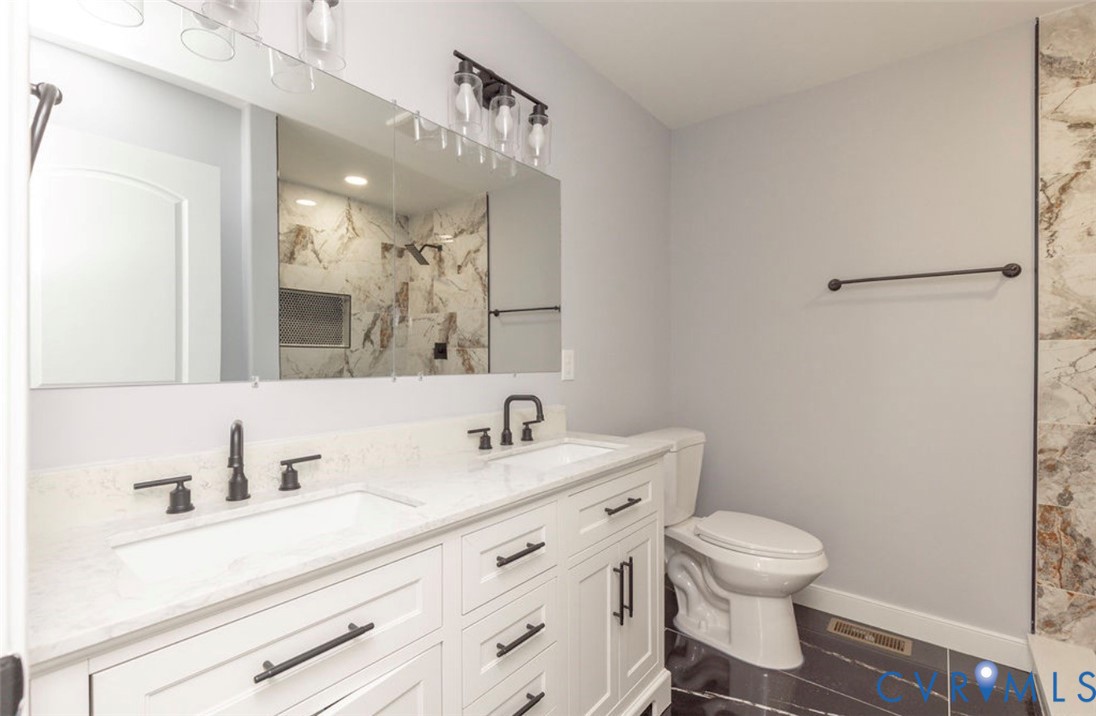 Double vanity with white cabinetry, quartz-surface countertops, rectangular undermount sinks, matte black hardware, and an oversized vanity mirror with overhead glass-shade lighting