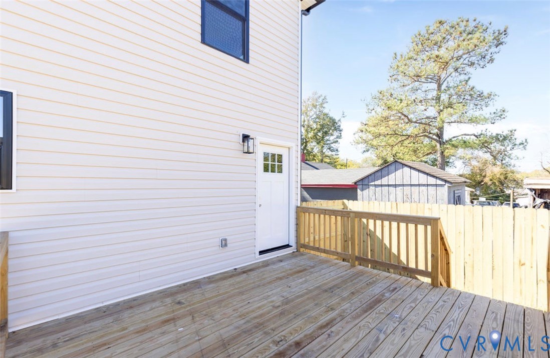 Wood deck featuring a natural finish, light-toned horizontal lap siding, a six-pane window door, and a perimeter wooden privacy fence