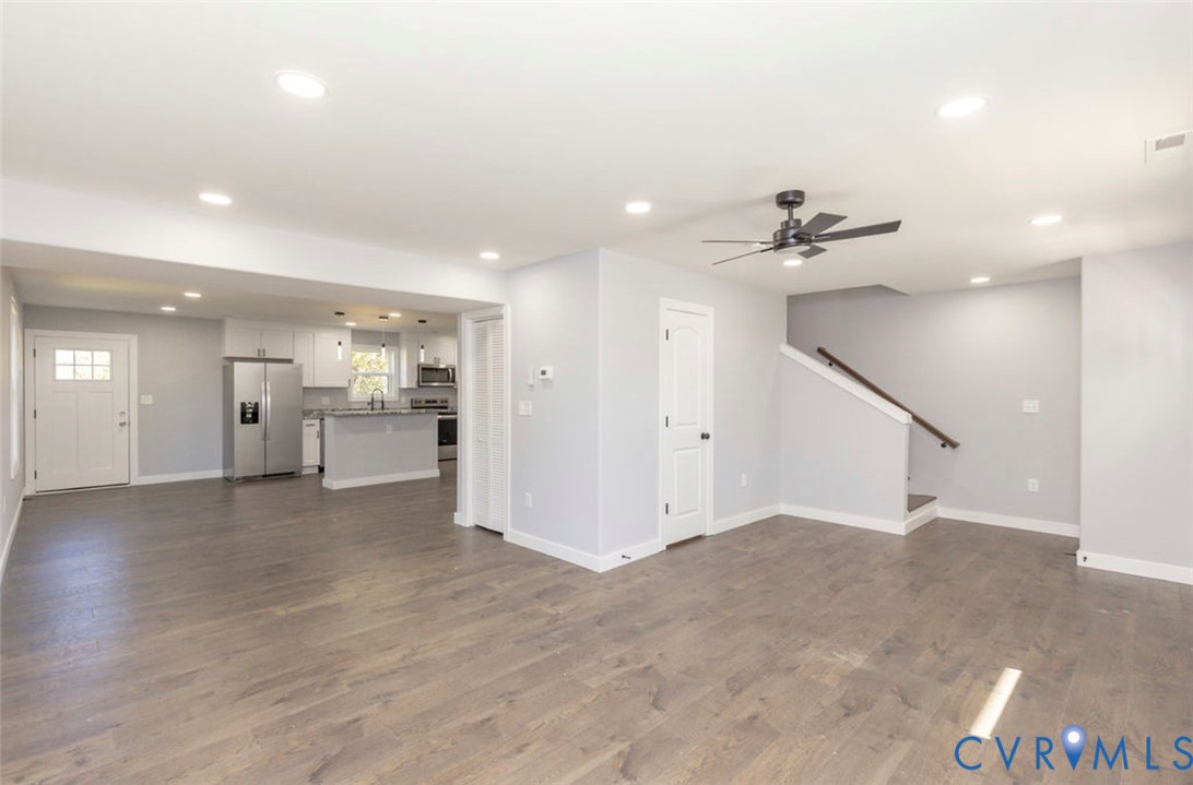 Open-concept interior featuring wood-finish flooring, recessed lighting, a modern ceiling fan, and white kitchen cabinetry with a peninsula