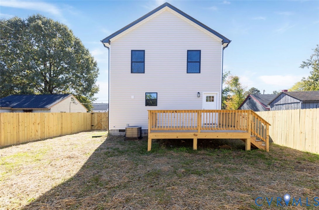 Exterior view featuring light-toned horizontal siding, a raised wood deck, and a fenced backyard