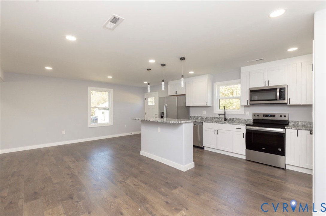 Kitchen featuring white cabinetry, stone-surface countertops, stainless steel appliances, wood-finish flooring, and pendant lighting