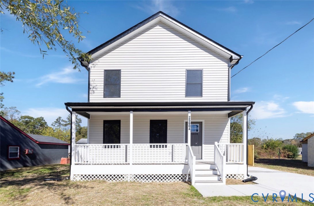 Two-story exterior featuring light-toned horizontal siding, a covered front porch with white lattice skirting, black-trimmed windows, and a concrete driveway Two-story exterior featuring light-toned horizontal siding, a covered front porch with white lattice skirting, black-trimmed windows, and a concrete driveway