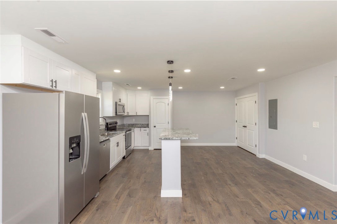Kitchen featuring white cabinetry, stone-finish countertops, stainless steel appliances, a center island with pendant lighting, and wood-finish flooring