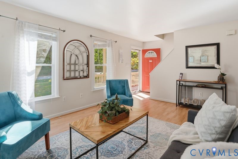 Interior space featuring wood-finish flooring, dual windows with natural light, and a prominent solid-color entry door