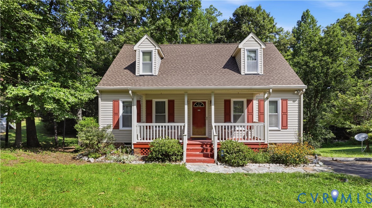 Cape Cod-style residence featuring horizontal siding, a covered front porch with white railing, twin dormer windows, and a shingled roof Cape Cod-style residence featuring horizontal siding, a covered front porch with white railing, twin dormer windows, and a shingled roof