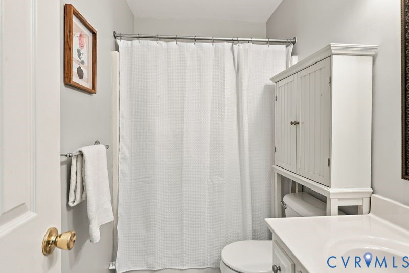 Bathroom featuring a vanity with integrated sink, over-the-toilet beadboard cabinetry, and a shower-tub combination with a metal tension rod