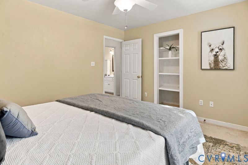 Built-in recessed shelving, ceiling fan with light fixture, and six-panel interior door