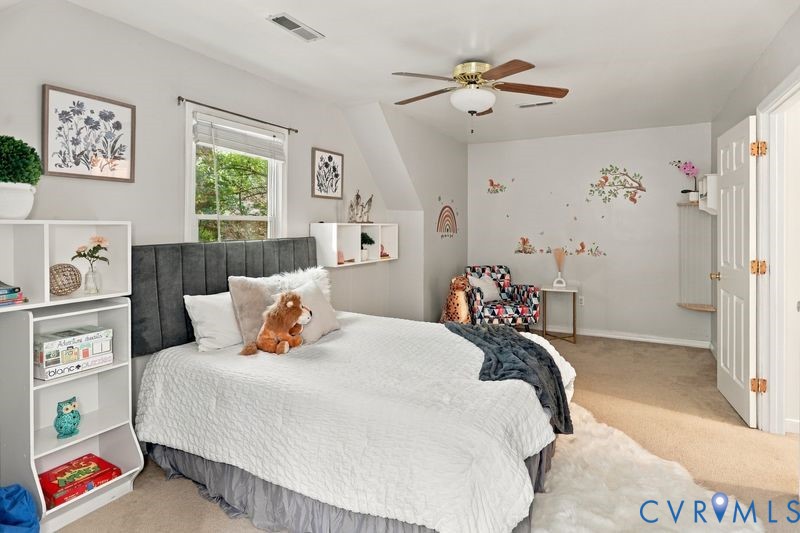 Bedroom featuring carpeted flooring, a ceiling fan, neutral wall paint, and built-in wall shelving