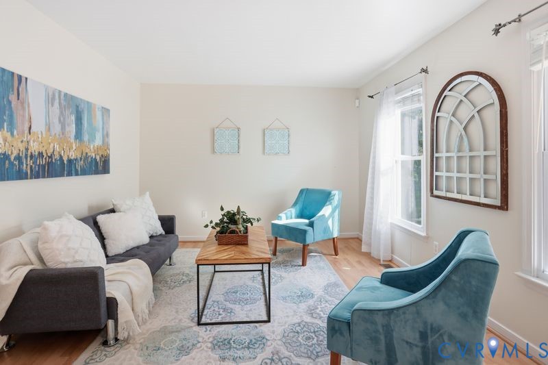 Neutral wall tones, wood-finish flooring, and natural light from tall windows
