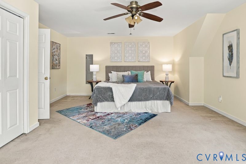 Spacious room featuring neutral carpeting, a multi-blade ceiling fan with integrated lighting, and dual hinged doors