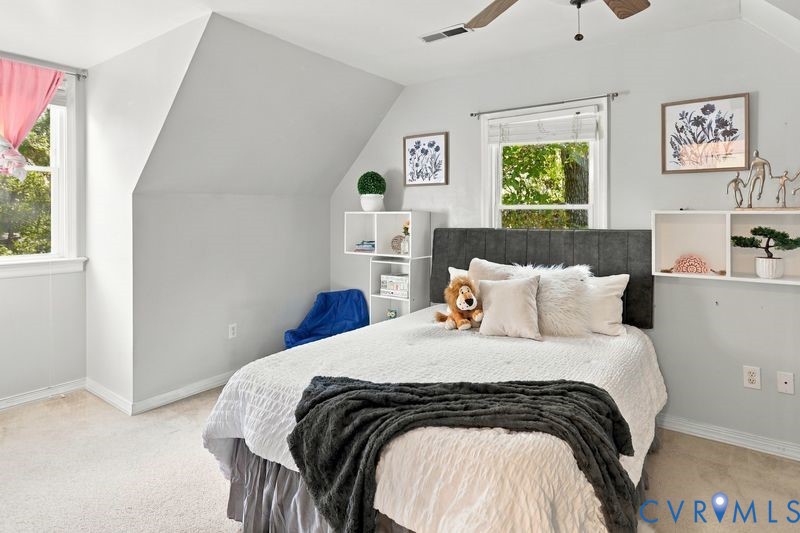 Room featuring sloped ceilings, wall-to-wall carpeting, windows with exterior tree cover, and built-in shelving units