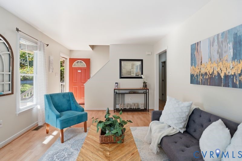Interior space featuring wood-finish flooring, neutral wall paint, and a front entry door with an arched glass inset