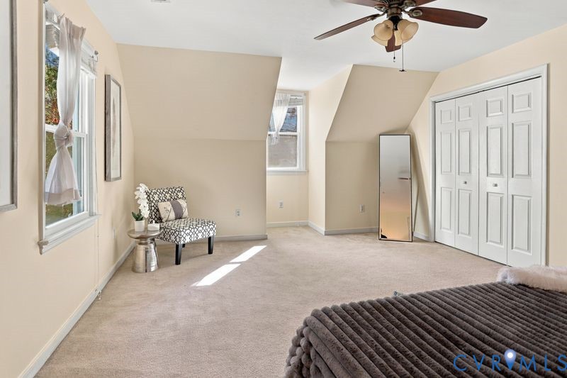 Neutral-toned interior space featuring vaulted ceilings, carpeted flooring, multiple windows, and a multi-panel bifold closet